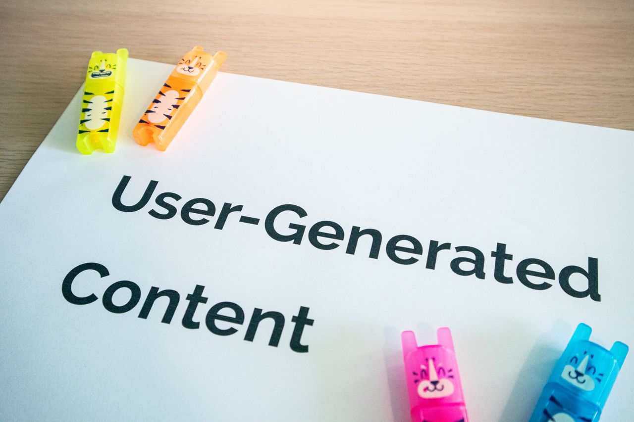 Bright highlighters resting on a User-Generated Content note placed on a wooden desk.